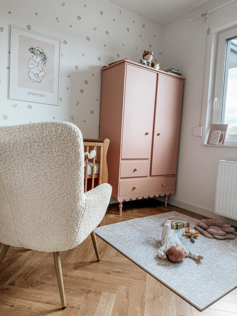 1. Baby lying on vintage beige foam puzzle playmat in nursery with pink wardrobe and crib