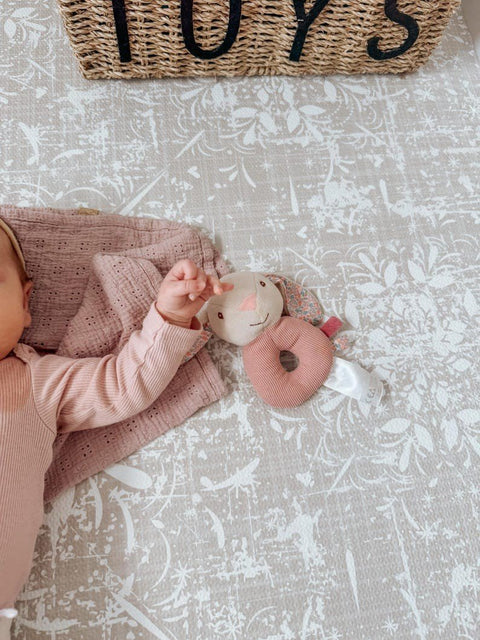 1. Baby's hand holding plush toy on vintage beige foam puzzle playmat with floral pattern