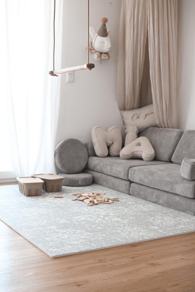 1. Cozy living room with grey sofa and OLYA KIDS vintage grey foam puzzle playmat on wooden floor, creating a serene atmosphere