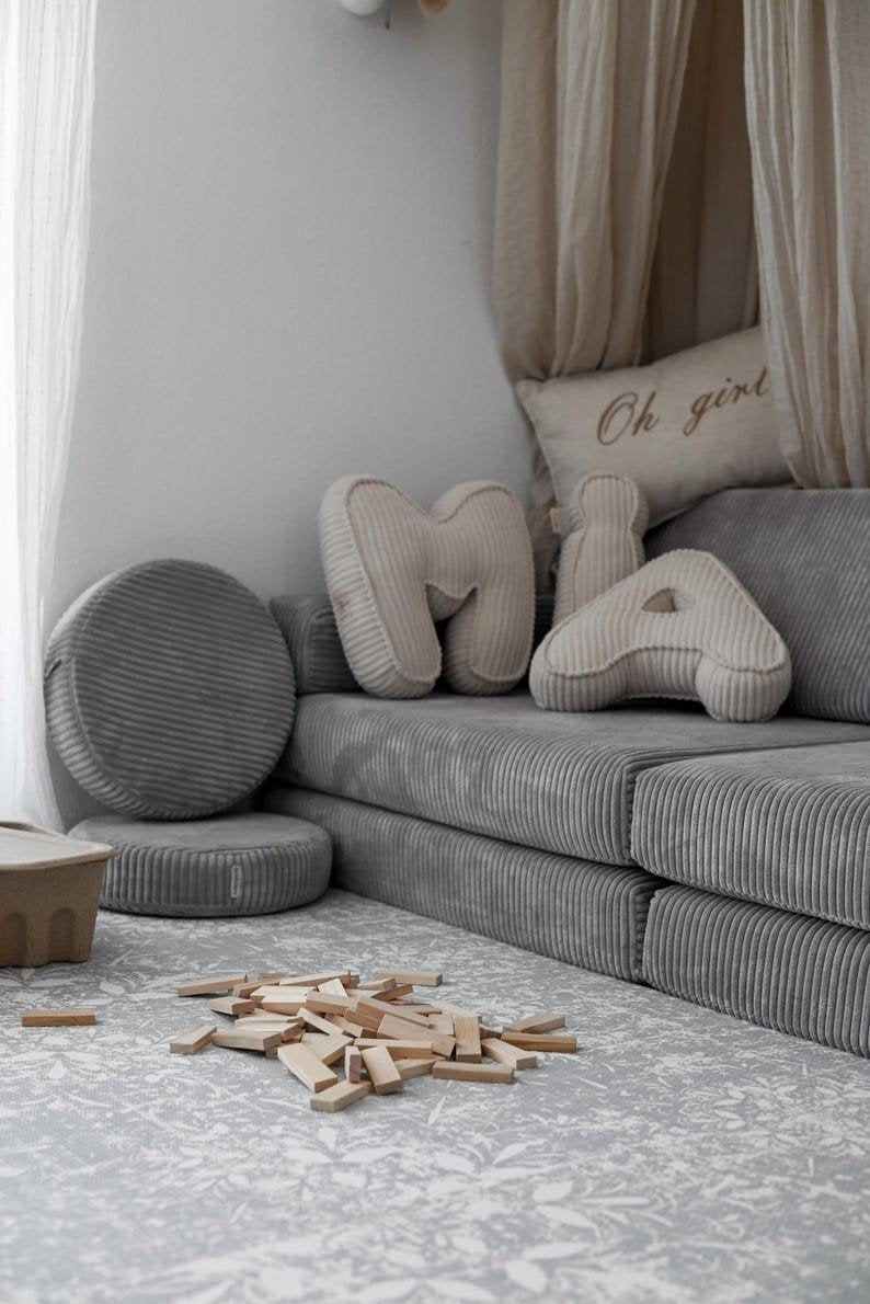 4. Grey sofa with decorative pillows and OLYA KIDS vintage grey foam puzzle playmat on floor, enhancing room's elegance