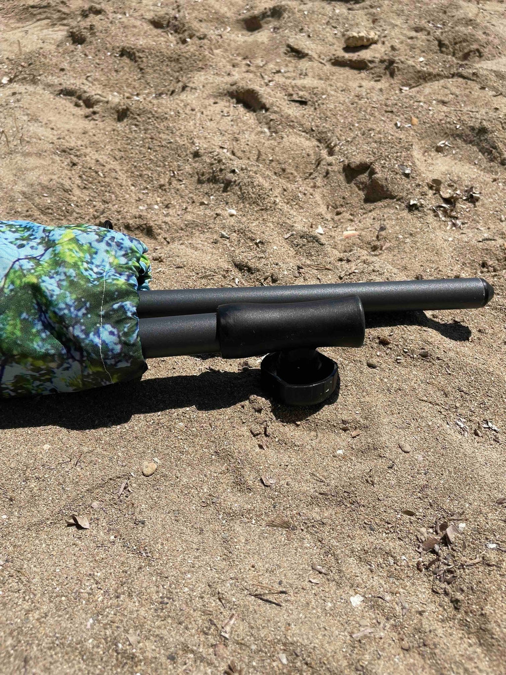 3. Close-up of HAPPYSWEEDS parasol pole and fabric with forest print on sandy beach