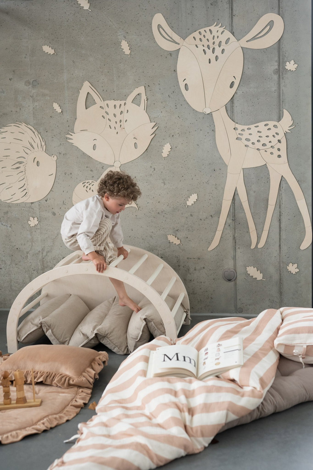8. Child playing in room with fox, hedgehog, and deer wooden wall decorations