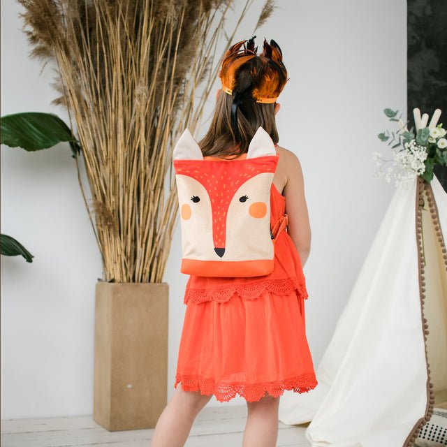 1. Girl wearing Muni kids fox backpack in lifestyle setting, showcasing adjustable straps and playful design