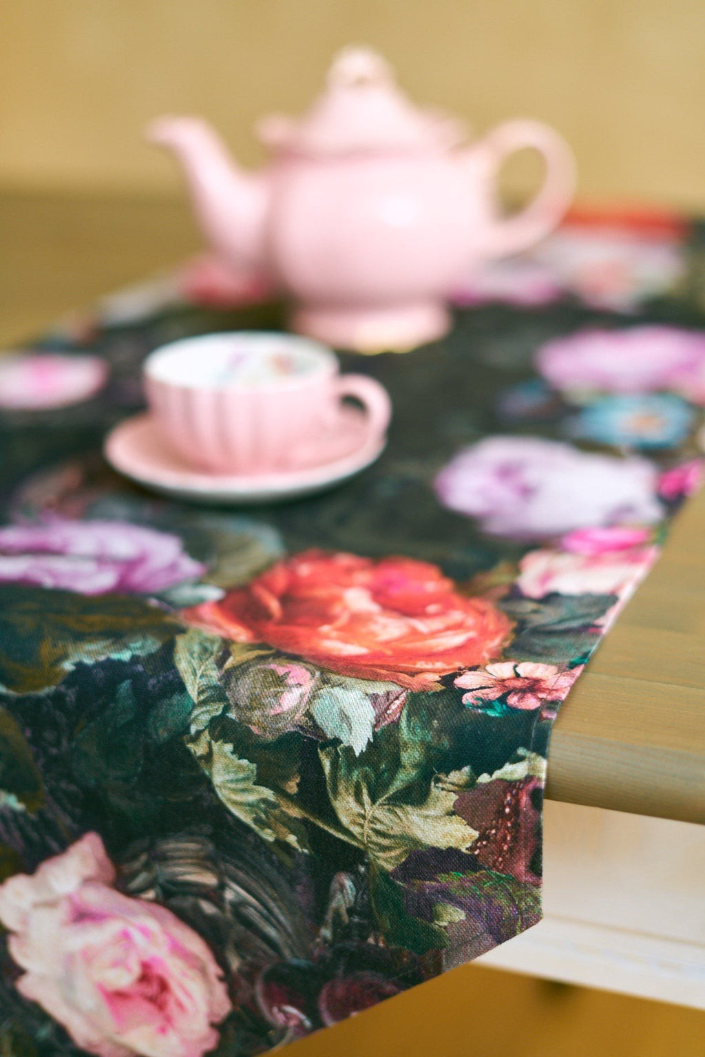 2. Close-up of Francine black table runner with floral design and tassels, featuring pink teapot and cup