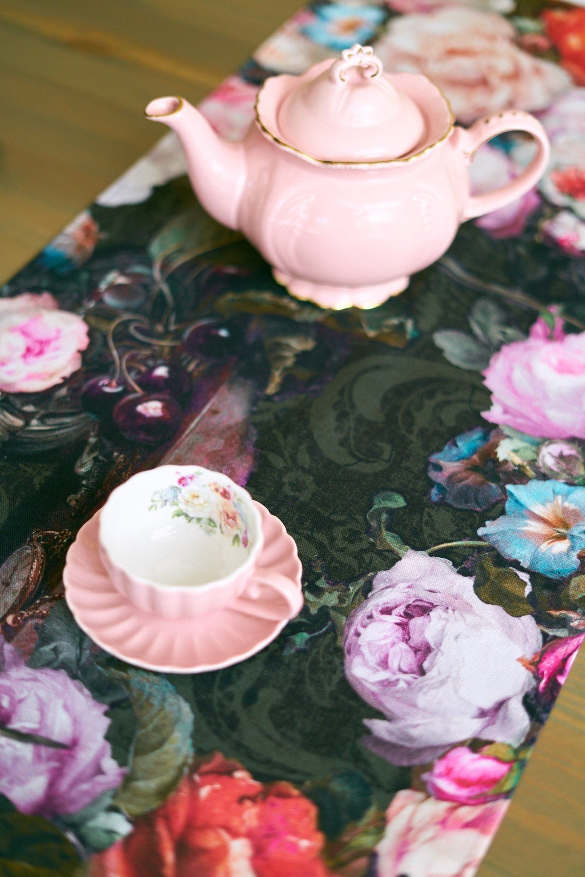 3. Detail of Francine black table runner with floral print, pink teapot and cup on wooden surface