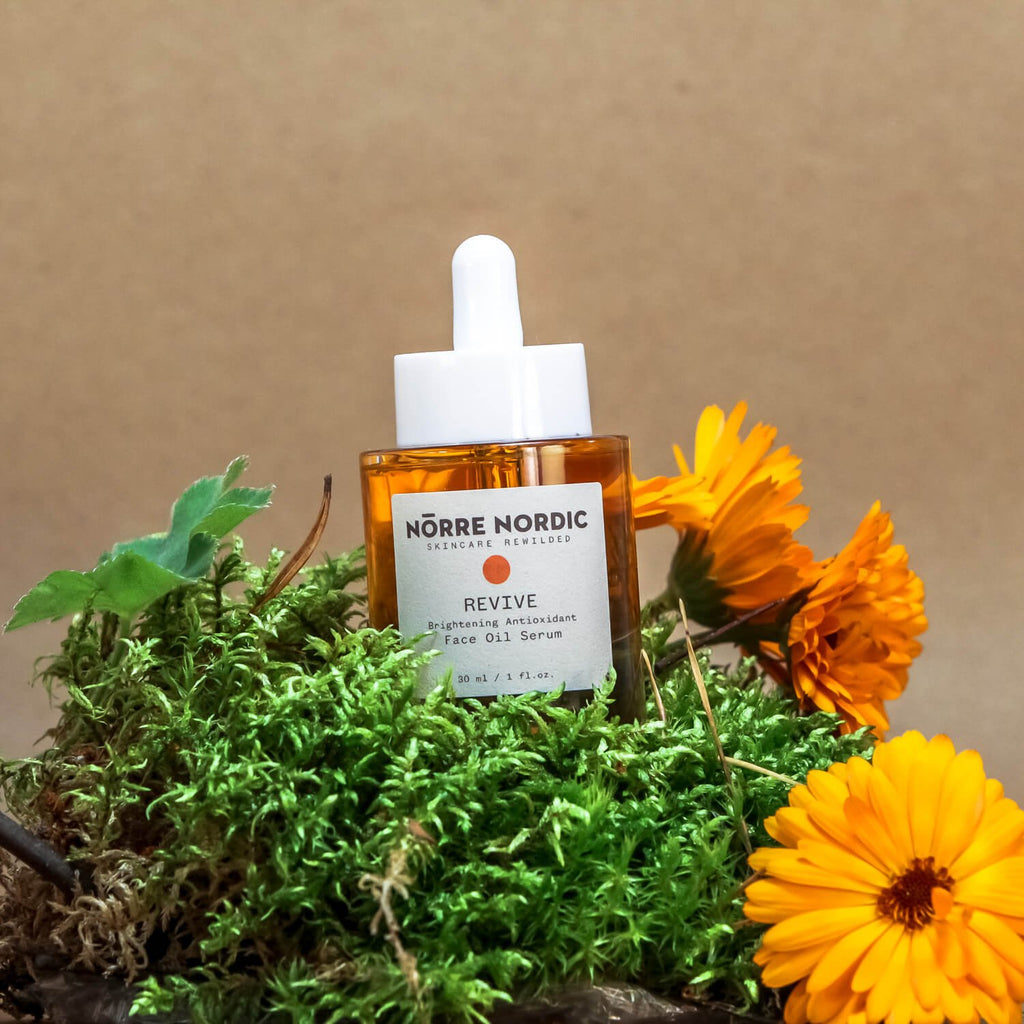 8. Nörre Nordic REVIVE Brightening Antioxidant Face Oil Serum bottle on natural setting with flowers