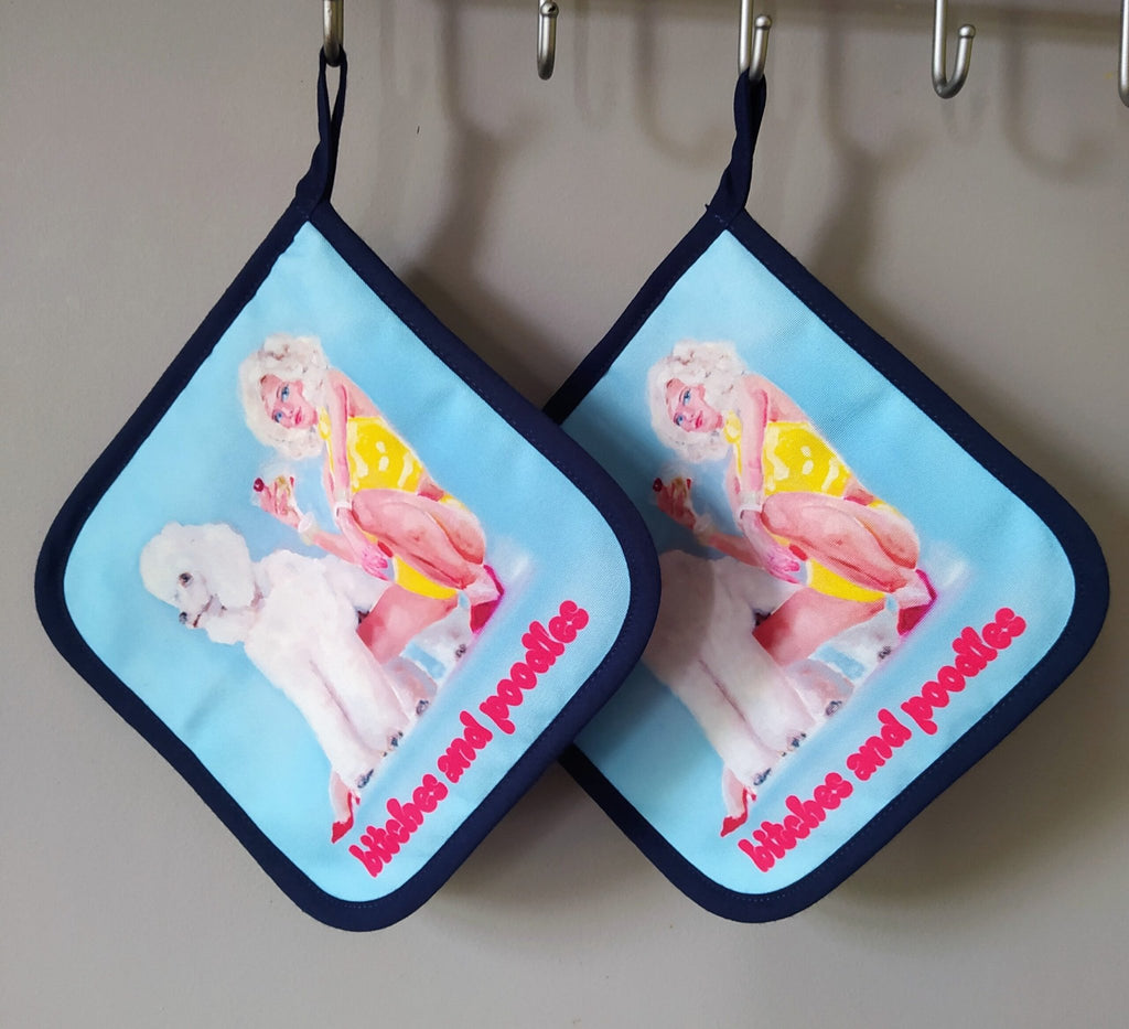 1. Two pot holders with pop art design of woman in yellow dress and poodle, text 'bitches and poodles' in red, hanging on hooks