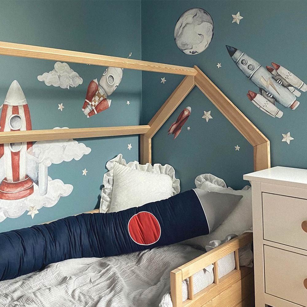 6. Space-themed child's room with watercolor rocket wall stickers on a blue wall above a wooden bed