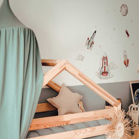 4. Child's room with watercolor rocket wall stickers above a wooden bed, featuring space-themed decor