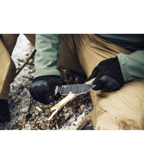 1. Person wearing black Mechanix M-Pact 3 gloves carving wood with a knife outdoors