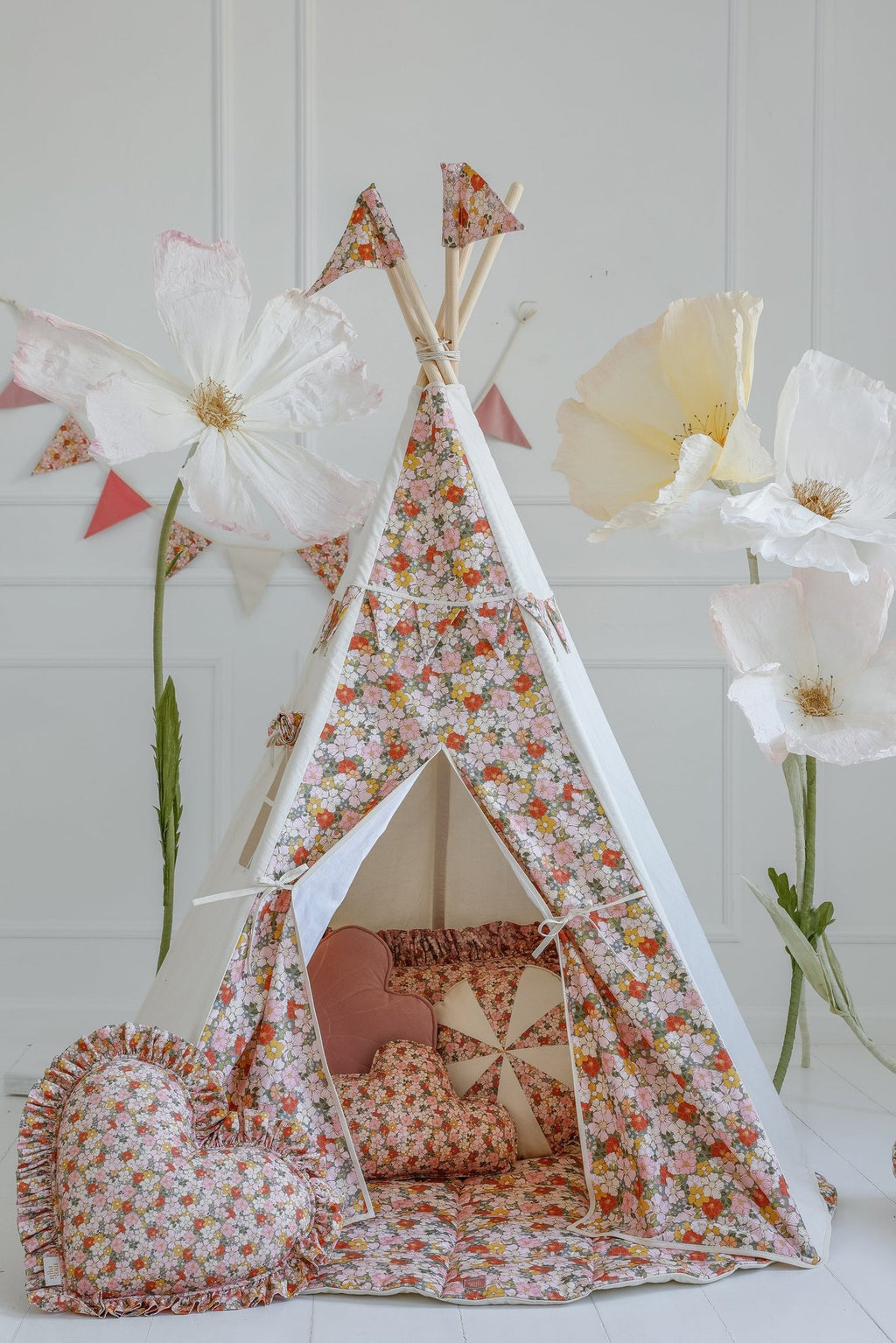 5. Floral teepee tent with matching garland and large paper flowers in a child's room