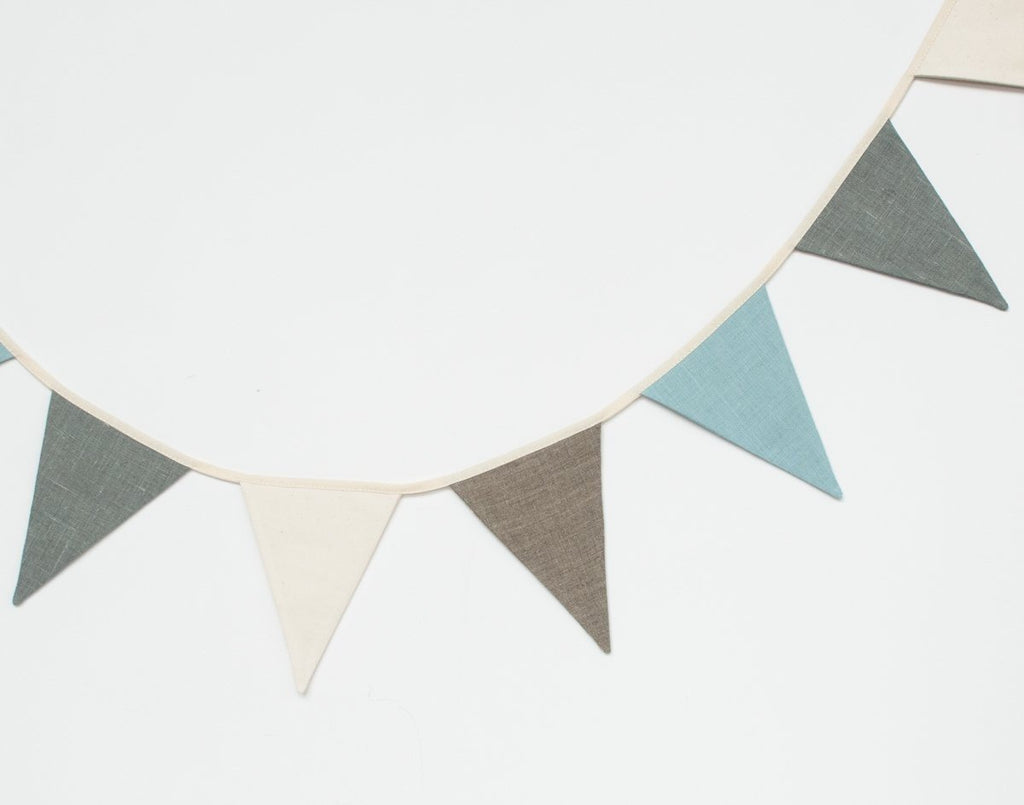 2. Studio shot of cream, grey, and teal linen garland with triangular pennants on white background