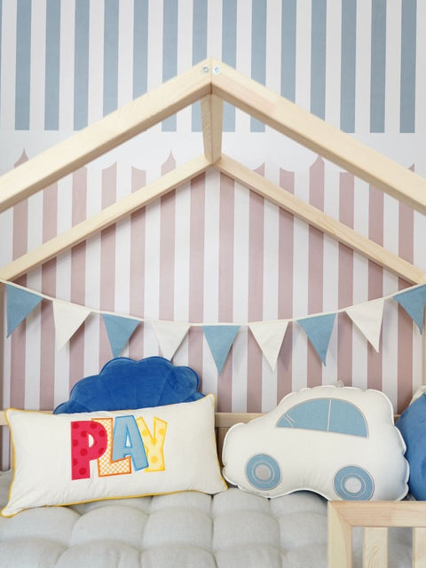 3. Close-up of children's bed with blue and white garland and play-themed cushions against striped wallpaper