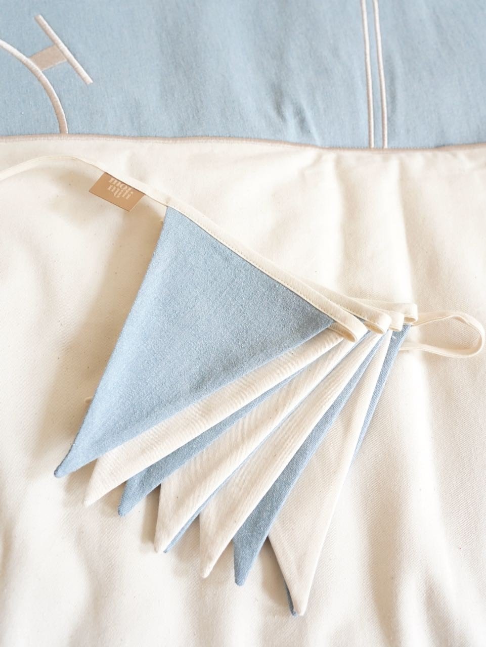 5. Close-up of folded blue and white triangular garland on a soft fabric surface
