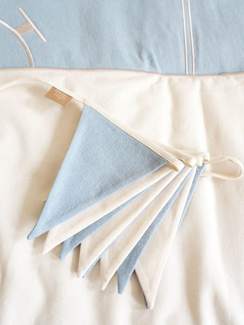 5. Close-up of folded blue and white triangular garland on a soft fabric surface