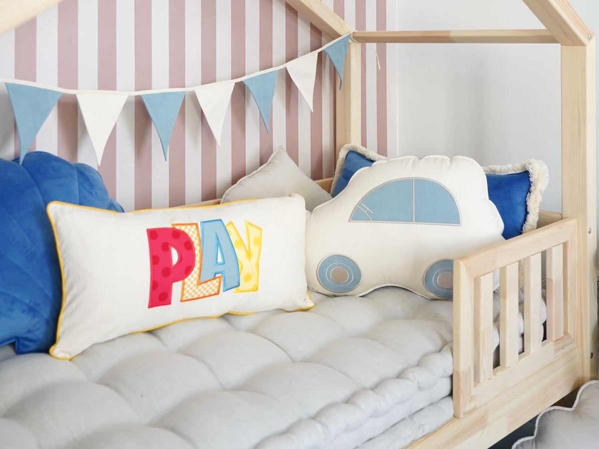 6. Children's bed with blue and white garland, play-themed cushions, and striped wallpaper