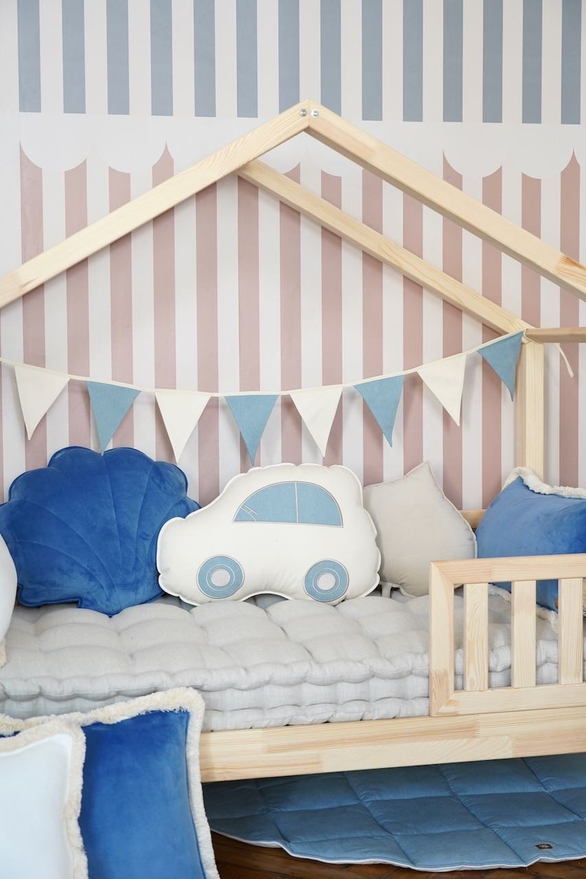 12. Close-up of wooden bed with blue and white garland and car-themed cushions