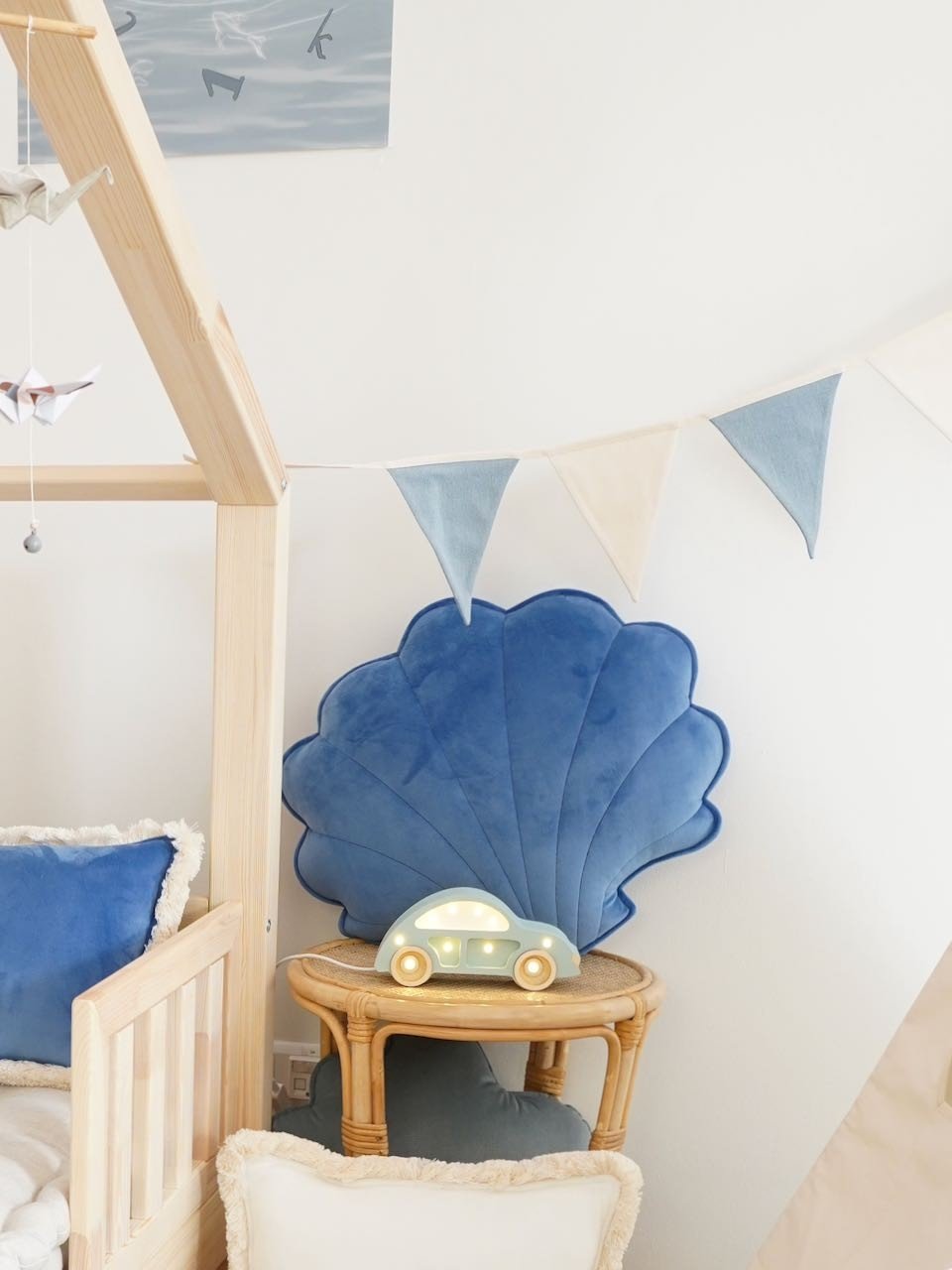 9. Corner of child's room with blue shell cushion, wooden furniture, and blue and white garland