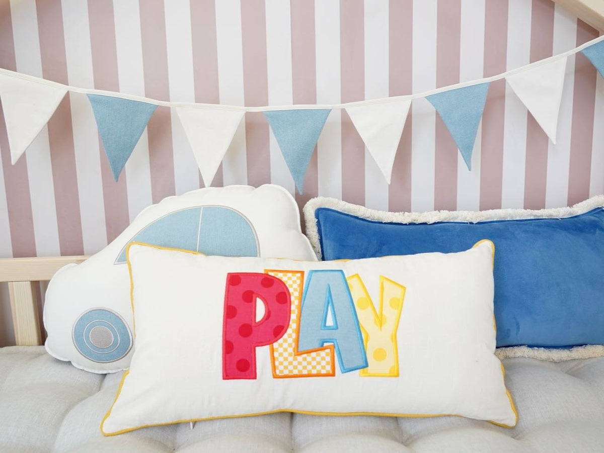 7. Close-up of play-themed cushion and blue and white garland in a child's room