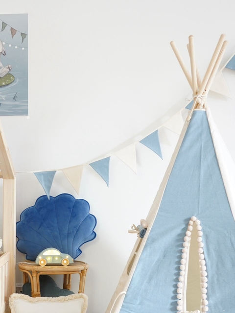1. Child's room with blue and white teepee tent, shell-shaped cushion, and blue and white garland hanging on the wall