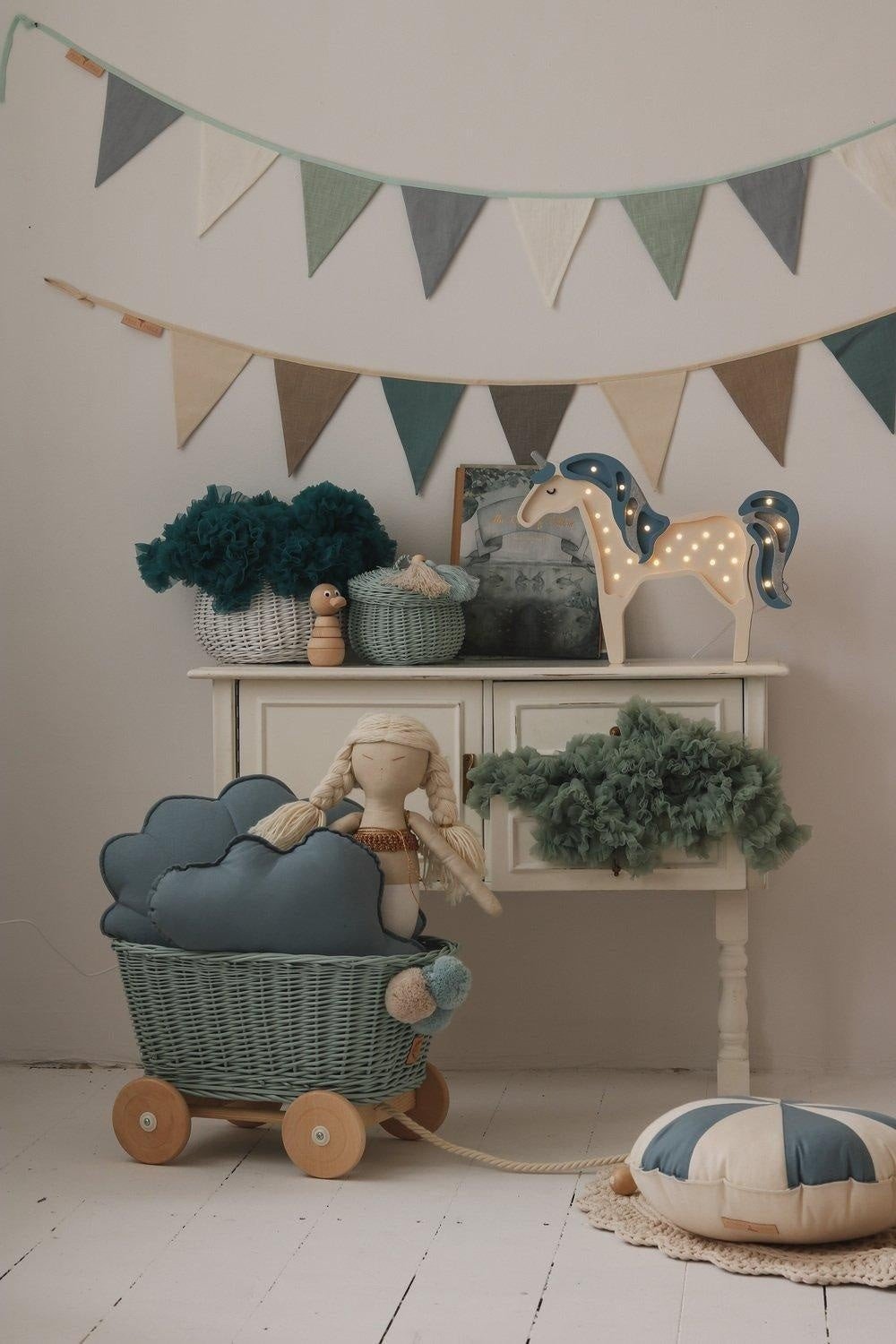1. Playroom with a mint, white, and grey garland above a dresser with toys and cushions