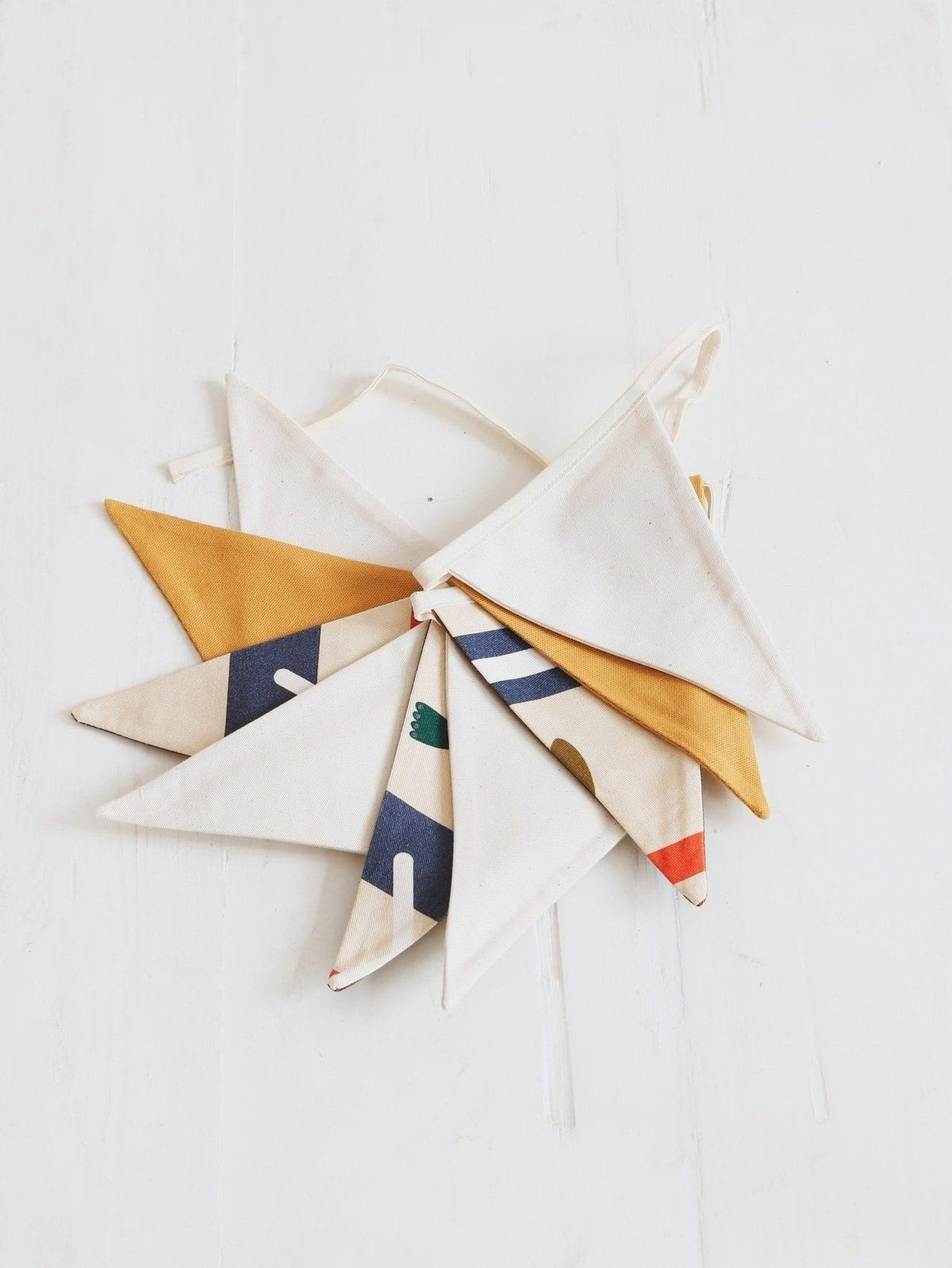 7. Flat lay of Moi Mili Native Vibe garland with geometric and mustard yellow pennants on white background