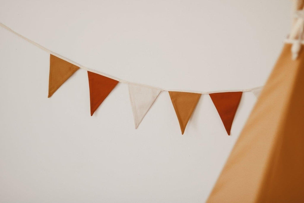 3. Close-up of ochre garland with white, honey, and red pennants hanging on a wall near a tepee