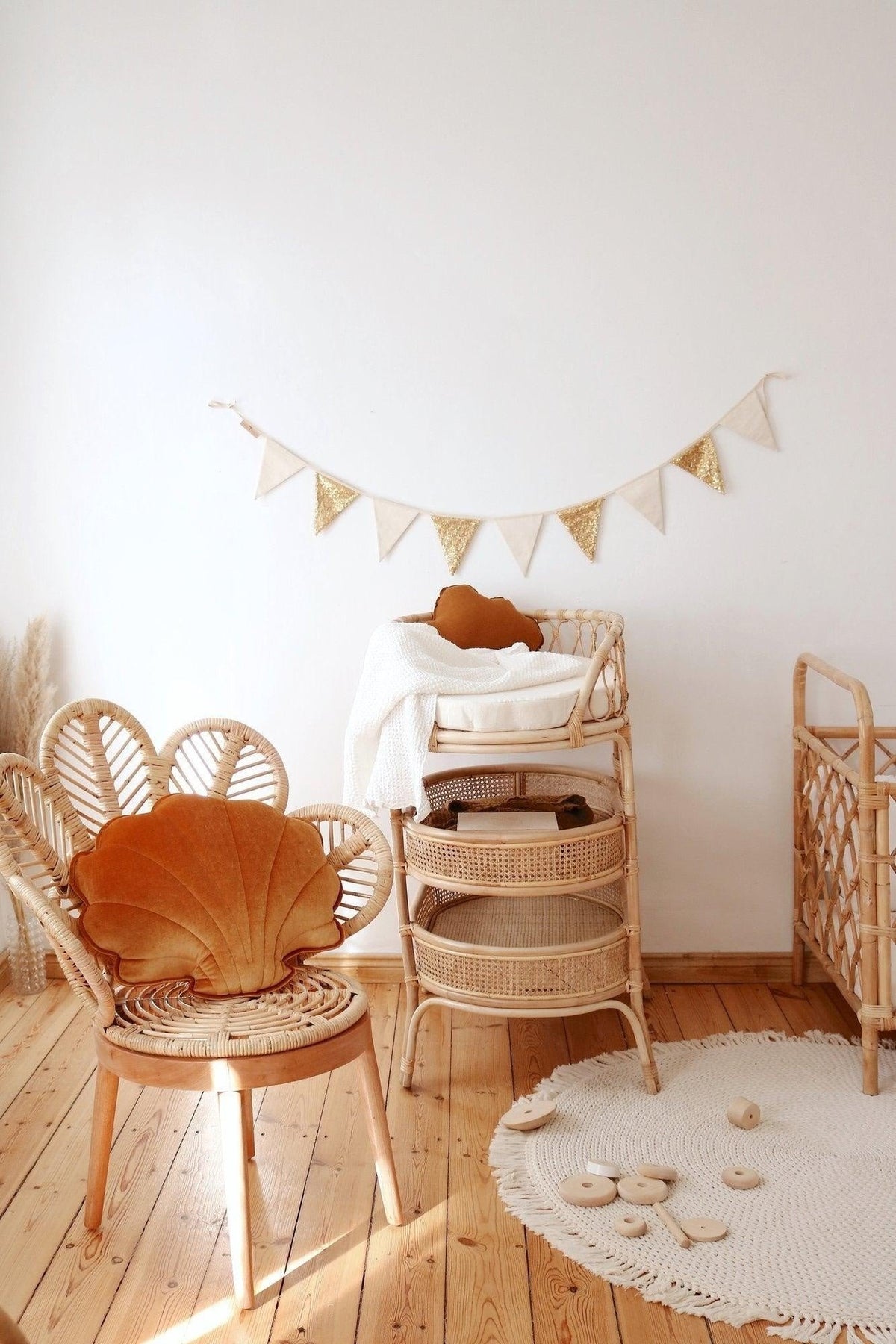 1. Children's room with gold and beige sequin garland hanging on white wall above wicker furniture