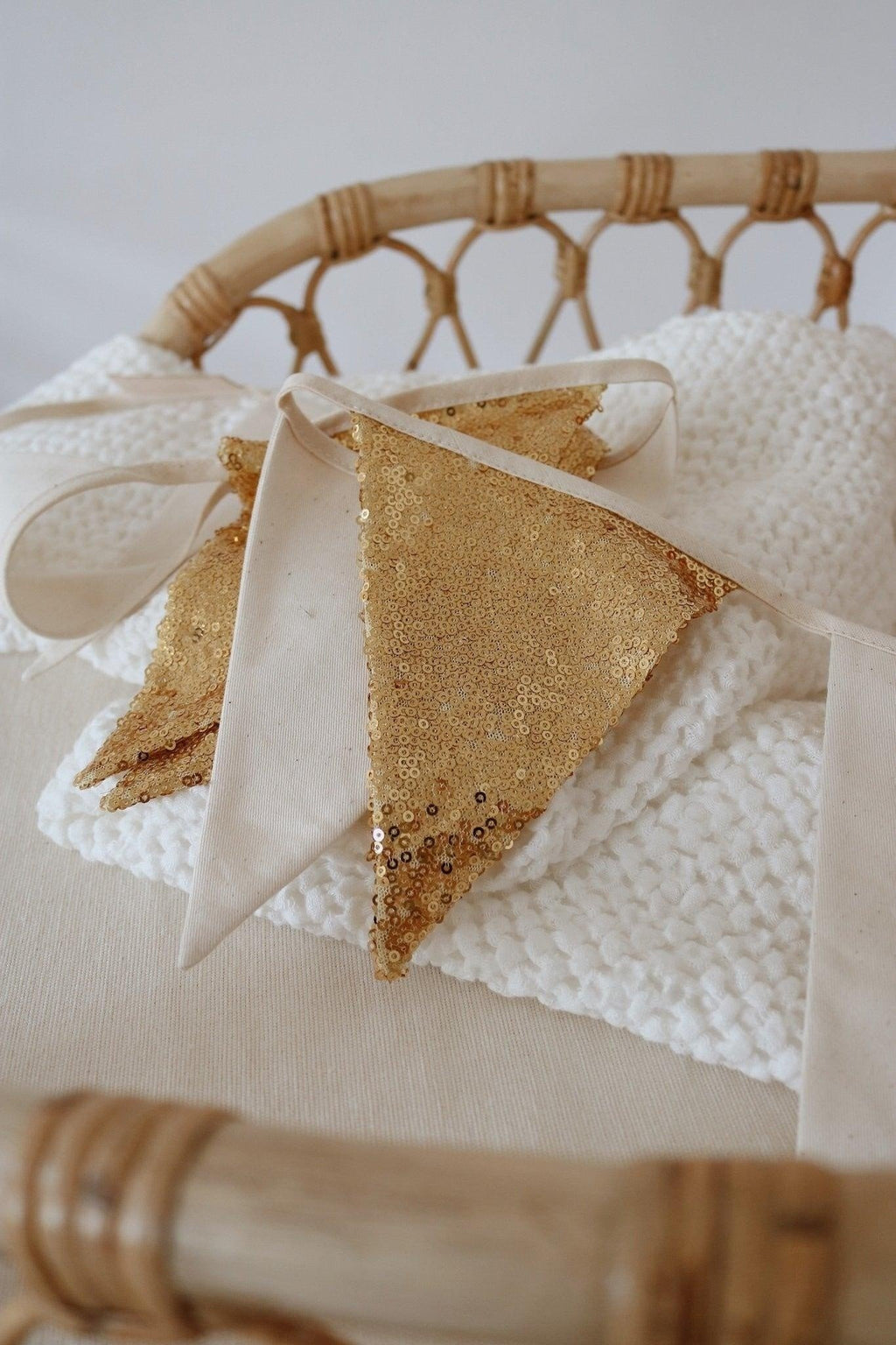 3. Close-up of gold sequin pendant on beige garland draped over white knitted fabric