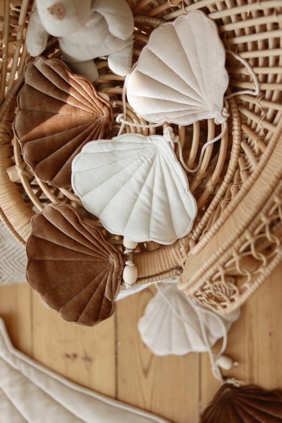 4. Close-up of velvet shell garland in brown, beige, and cream on a rattan surface with wooden beads