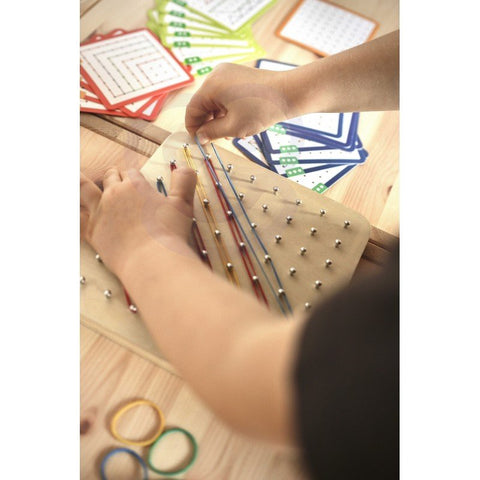 5. Child's hands arranging rubber bands on Woopie Green Geoplan board with pattern cards in background
