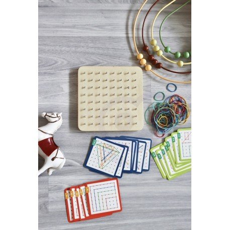 8. Woopie Green Geoplan set with wooden board, rubber bands, and pattern cards on grey floor with decorative items