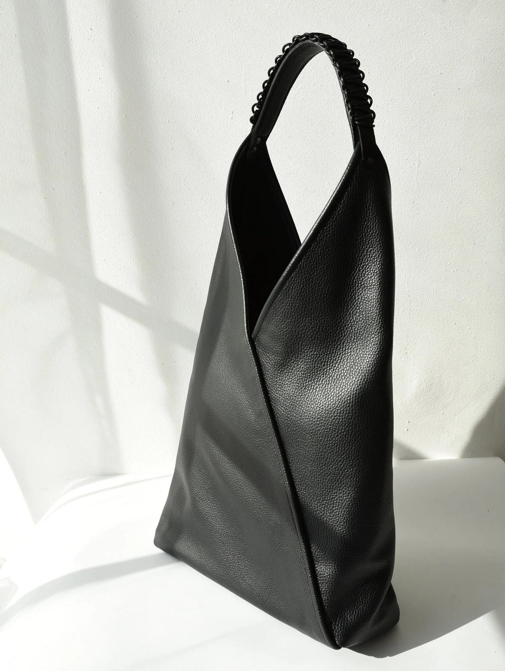1. Black leather tote bag Ateena by Gerda Retter Design, showcasing Nordic simplicity and geometric elegance in a studio setting