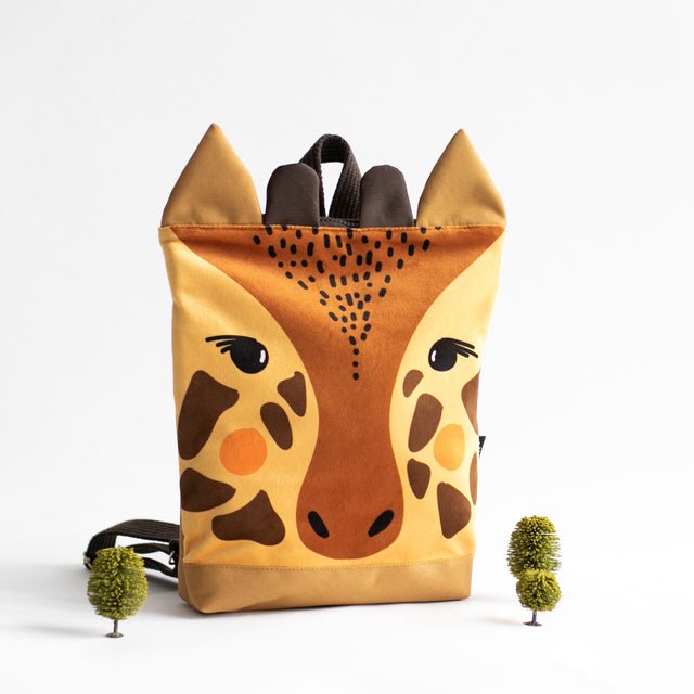 6. Muni giraffe backpack in studio with decorative plants, highlighting playful design