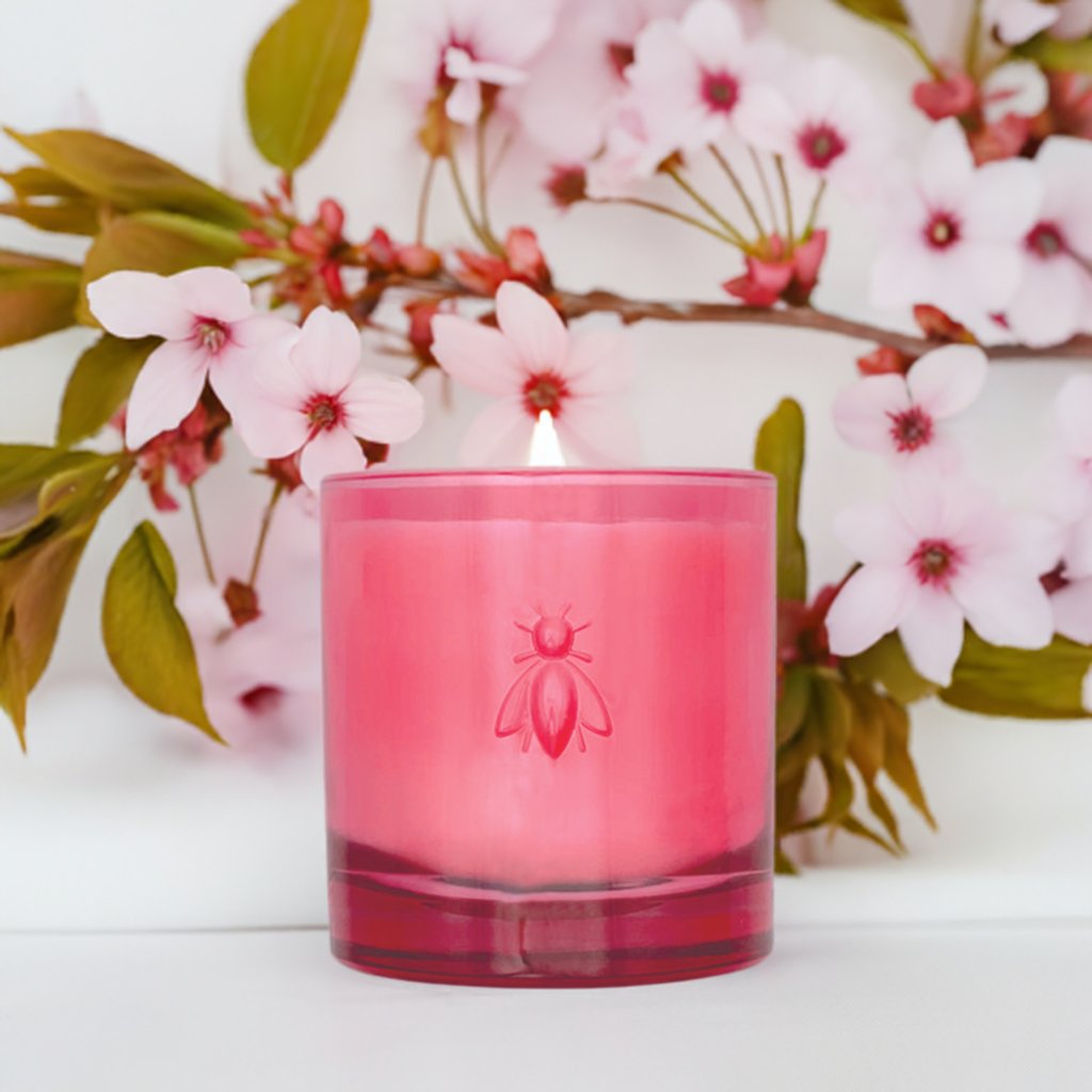1. Cherry Blossom Bee Candle by La Rochère in pink glass with bee design, surrounded by cherry blossoms, creating a serene atmosphere