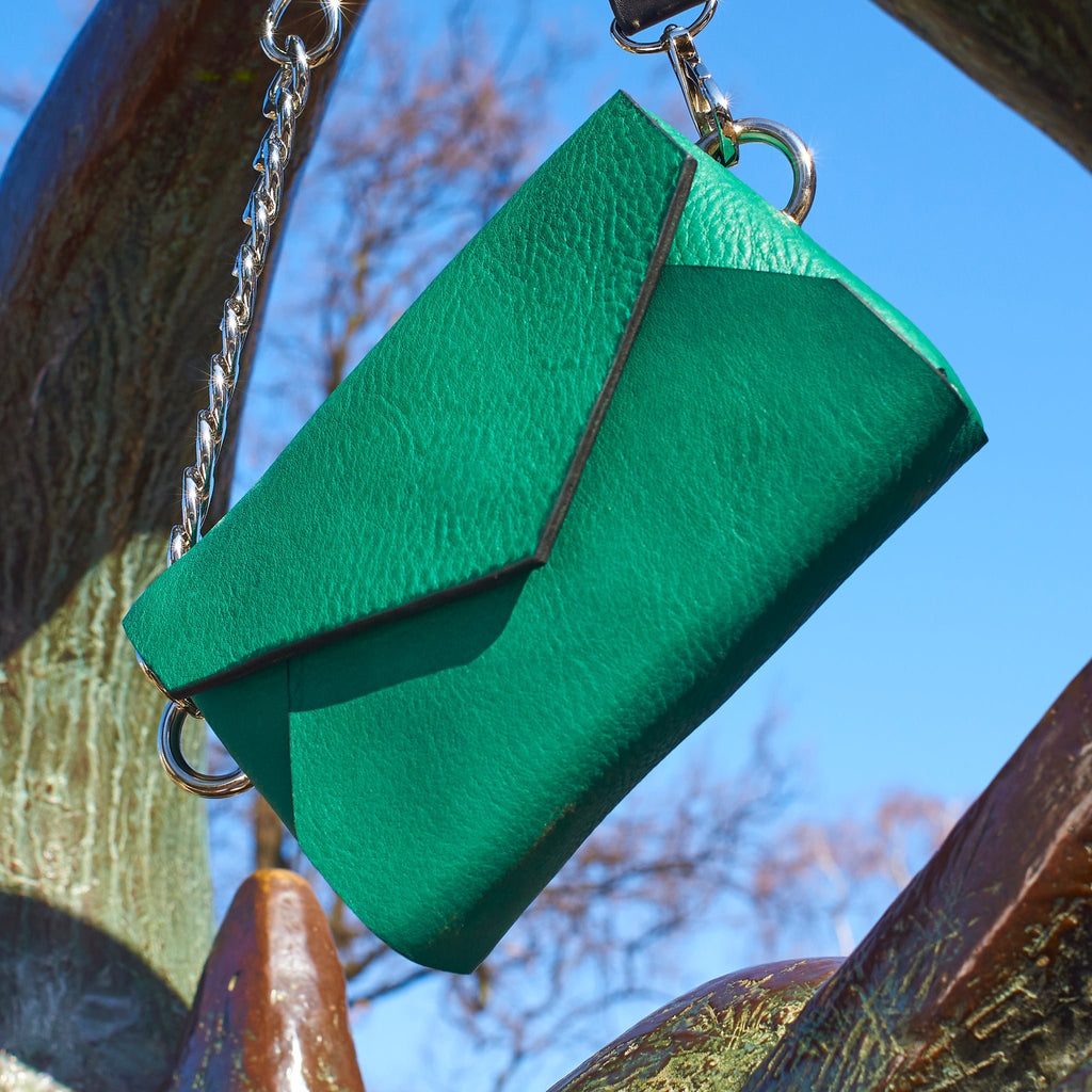 3. Daz Studio green leather envelope bag hanging outdoors with silver chain detail