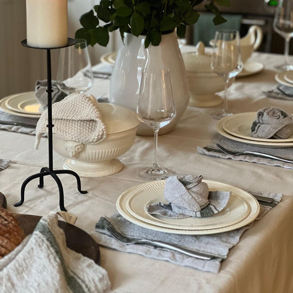 6. Elegant dining table with green striped placemats, white plates, and glassware, featuring a candle and greenery centerpiece