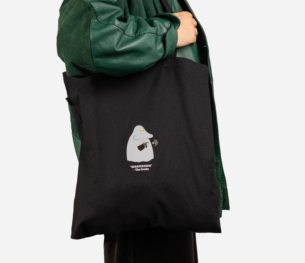 1. Black Moomin The Groke tote bag carried by a person in a green jacket, showcasing eco-friendly design