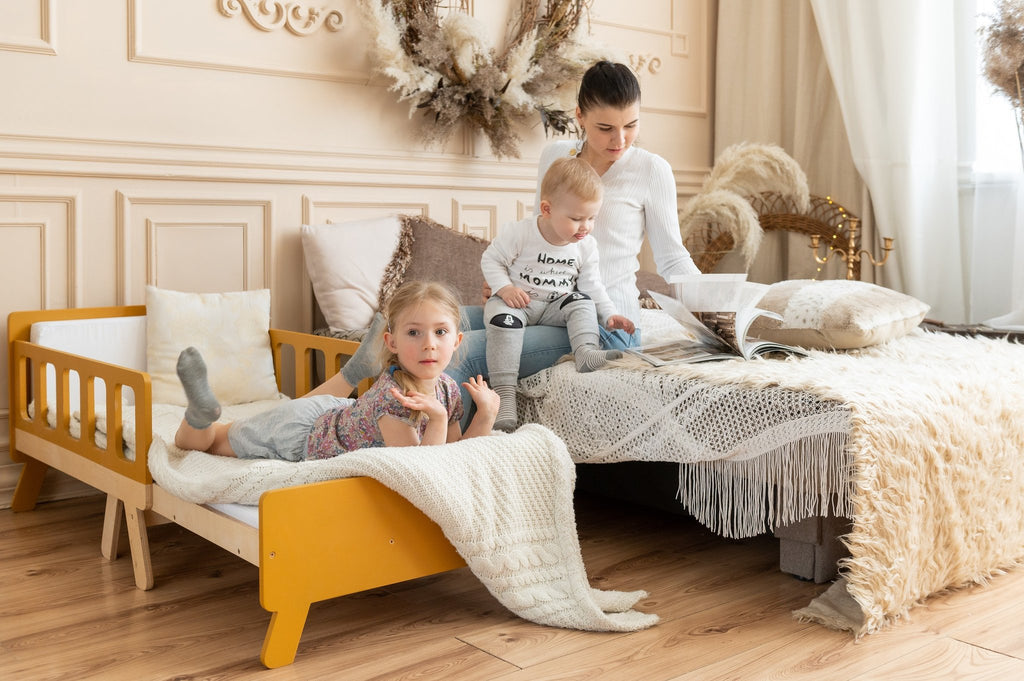 2. Woman with two children on yellow growing bed and large bed in cozy room with decorative elements