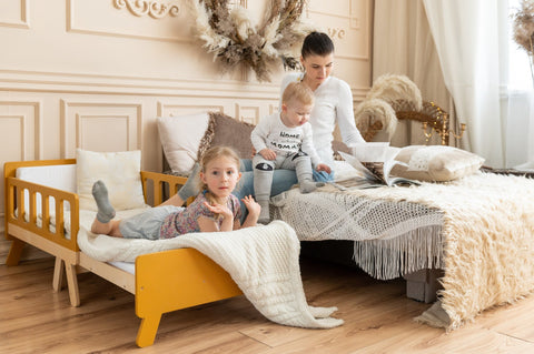 2. Woman with two children on yellow growing bed and large bed in cozy room with decorative elements