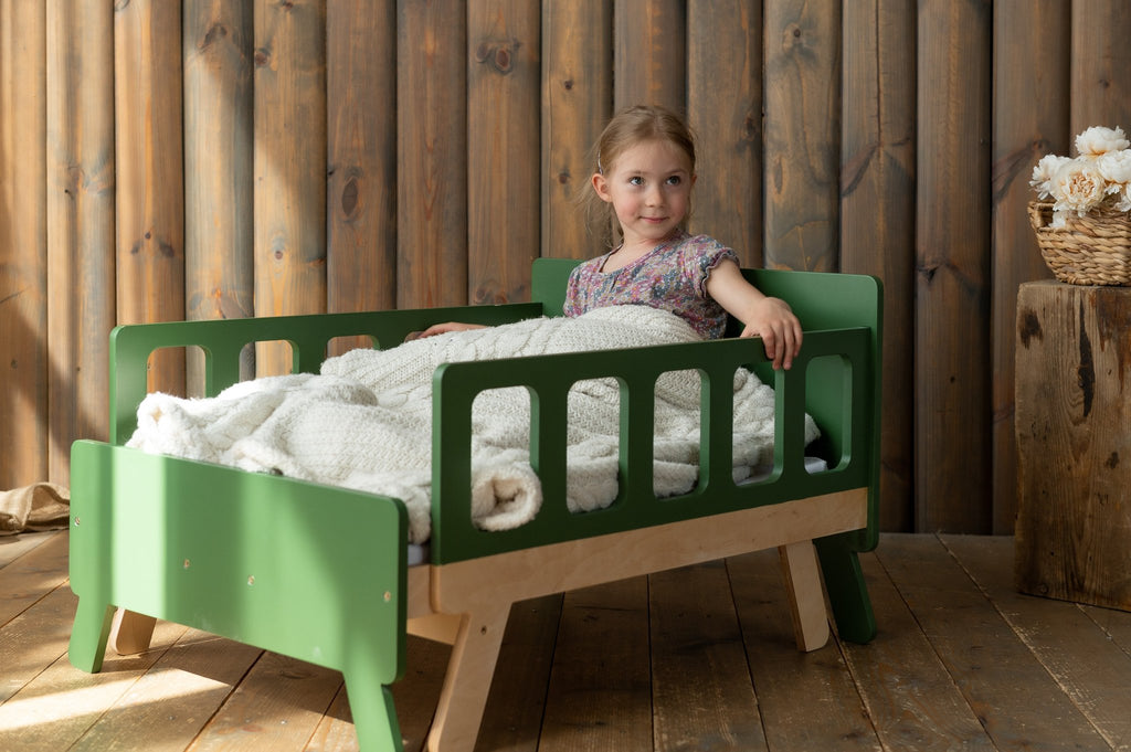 6. Child sitting on green growing bed with white bedding in wooden room