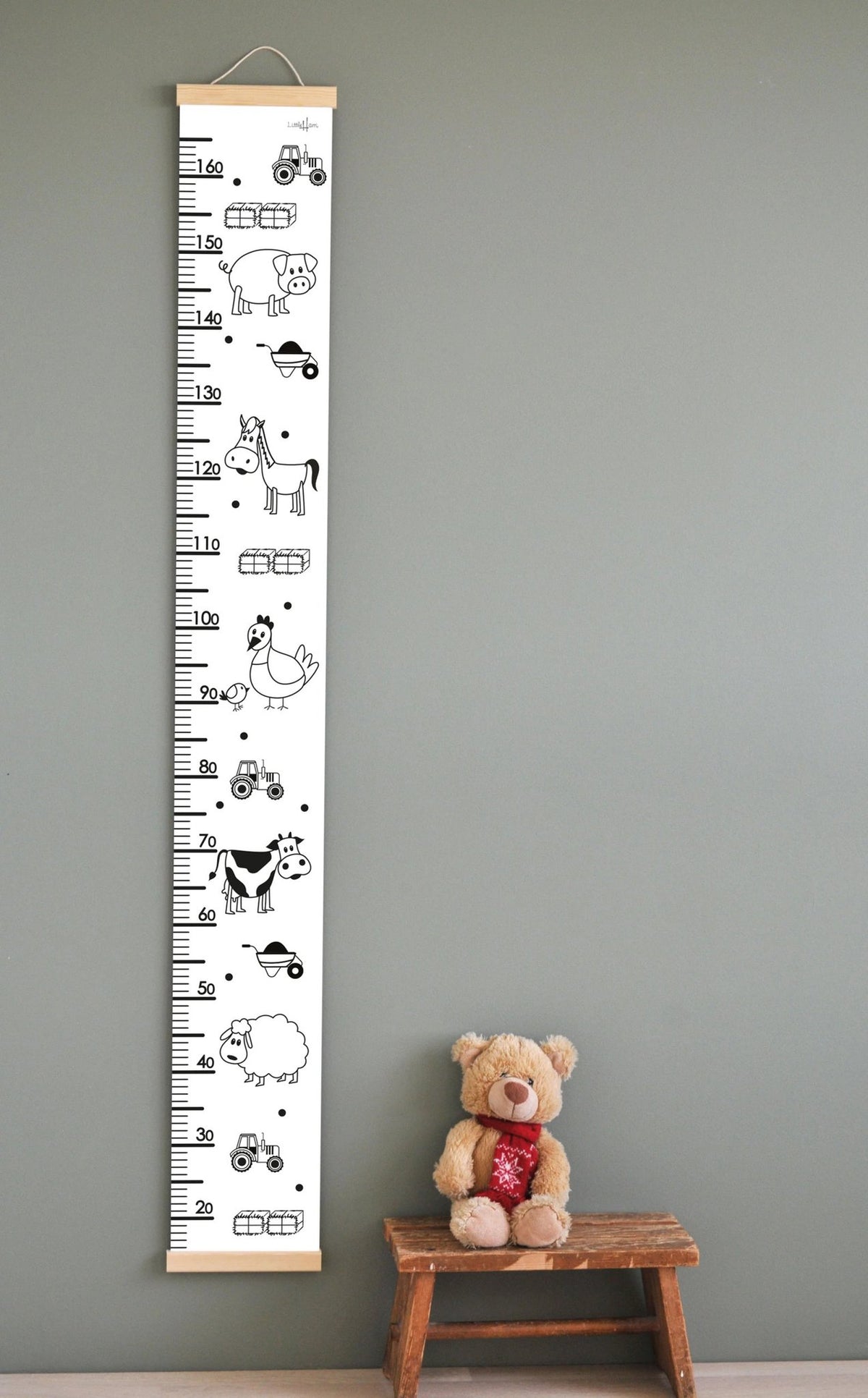 1. Children's growth chart with farm animal illustrations, including a horse, cow, and sheep, hanging on a wall with a teddy bear on a wooden stool below, featuring a measurement scale up to 165 cm.