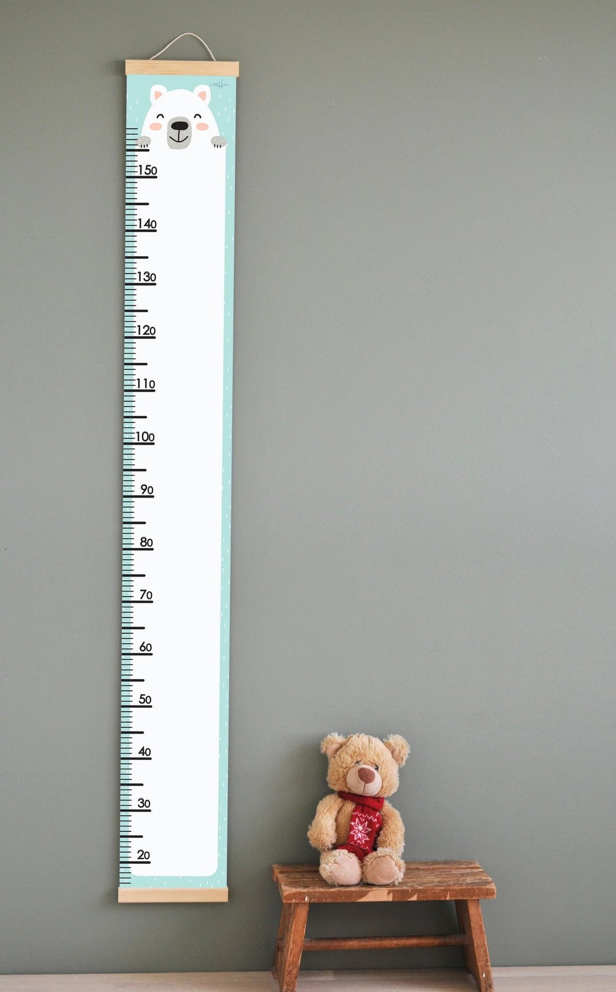 1. Kids' growth chart with polar bear illustration on wall, featuring measurement scale up to 165 cm, wooden slats, and attached string for hanging, next to teddy bear on wooden stool