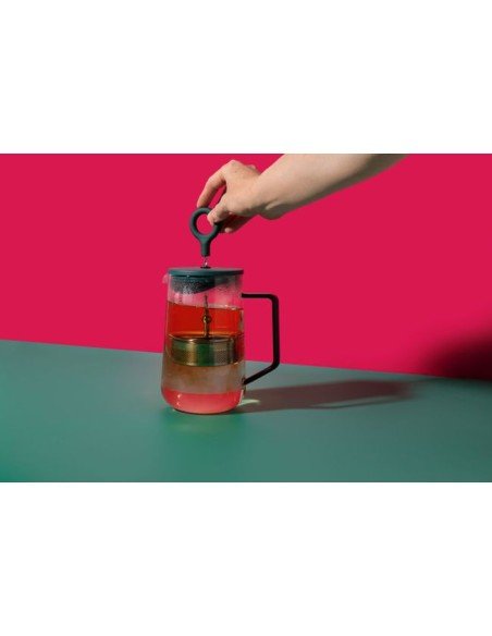 6. Hand using La Cafetière Gyro Teapot with red background, showing infuser in action