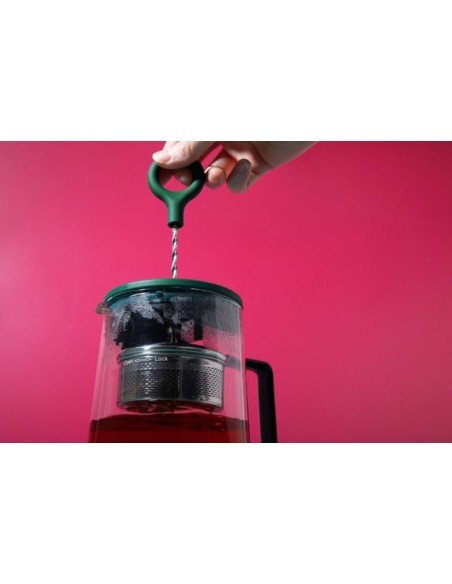 7. Close-up of hand turning plunger on La Cafetière Gyro Teapot against red background
