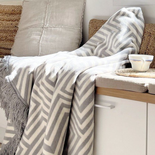 1. Gray and white Labbvenn pet blanket with geometric patterns draped over a cozy bench with neutral cushions and a cup on a tray