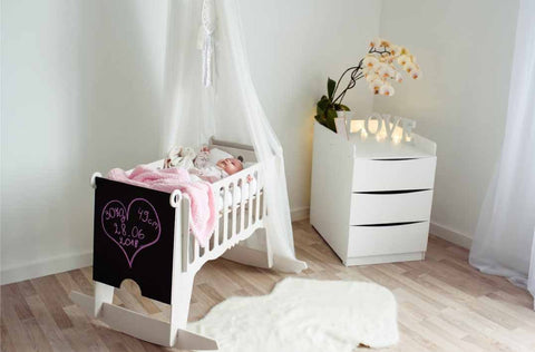 1. Baby sleeping in white Adensen birchwood cradle with pink blanket in cozy nursery setting