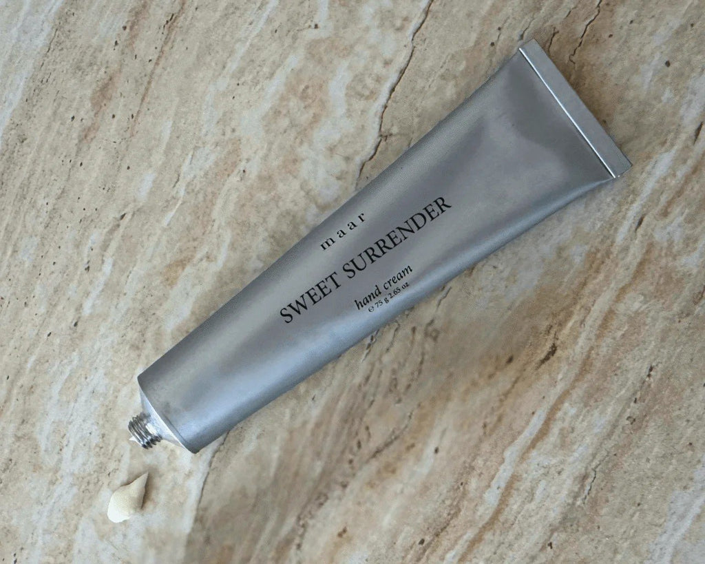 2. Silver tube of maar Sweet Surrender hand cream on marble surface with cream dollop