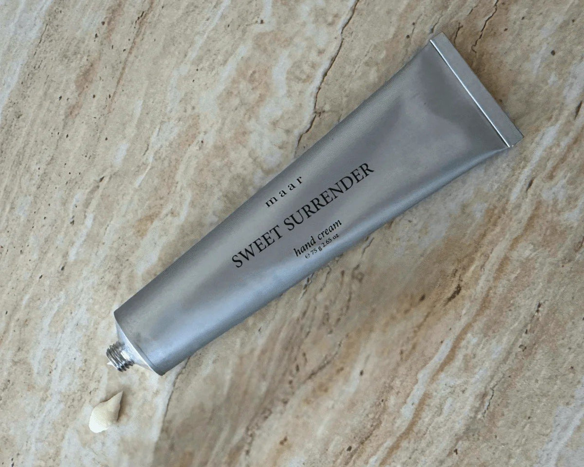 2. Silver tube of maar Sweet Surrender hand cream on marble surface with cream dollop