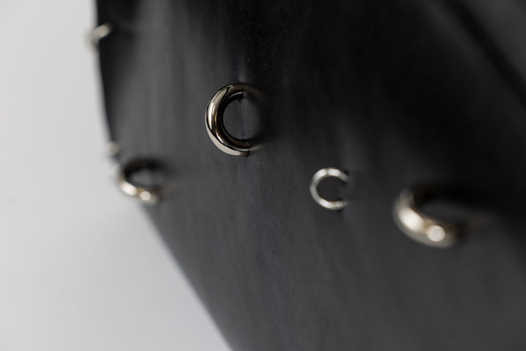 3. Close-up of silver decorative rings on black leather ARINA handbag